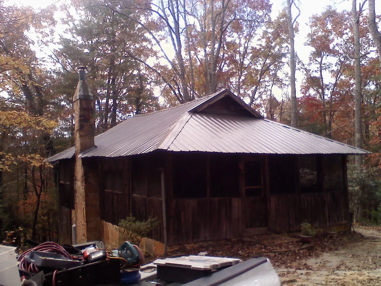Brown metal hip roof on an old cabin with a stone chimney in Athens
