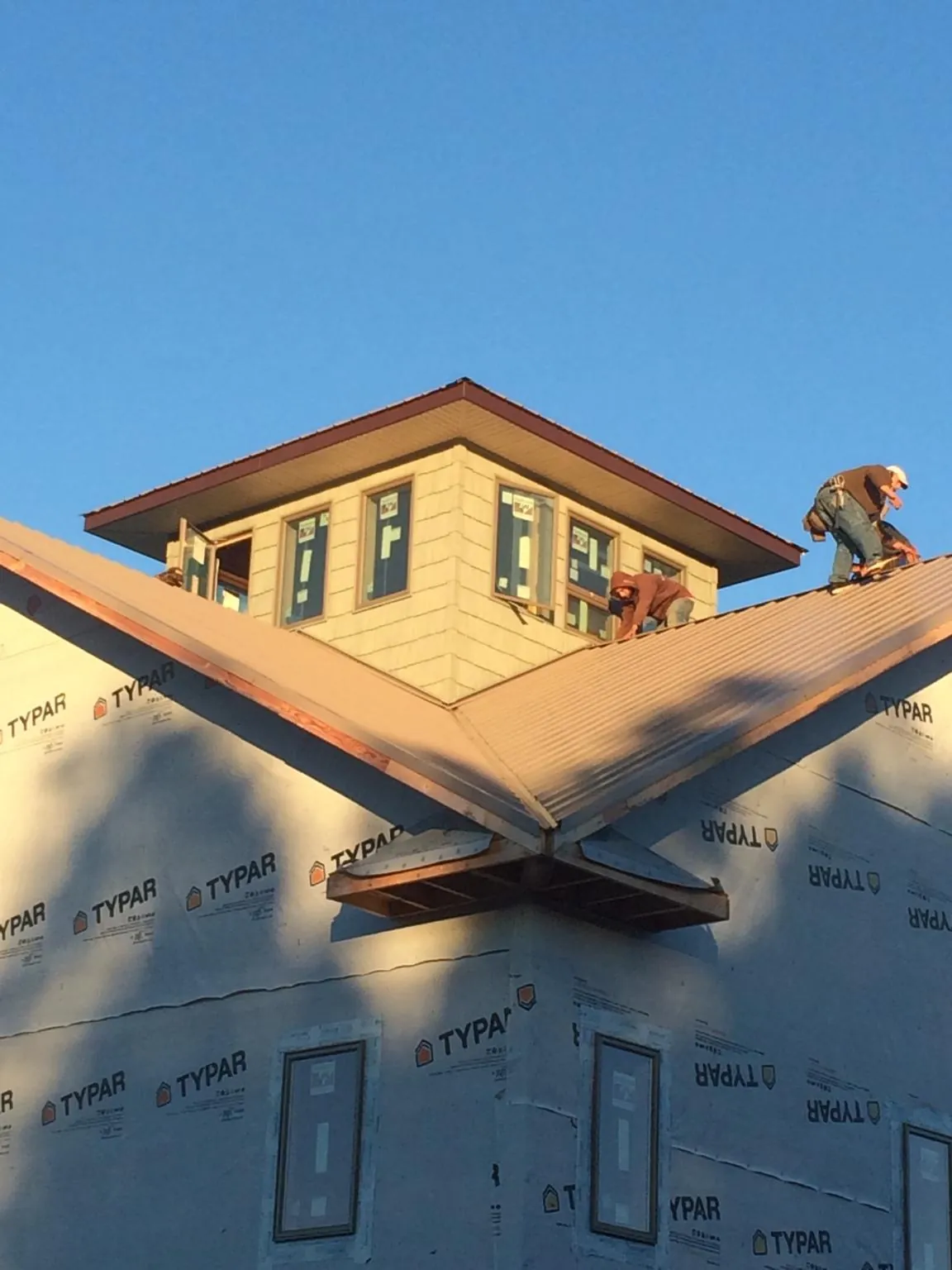 Roofers working around a rooftop cupola on a new metal roof at sunset — Roof Waterproofing in Athens by Roofing Brothers